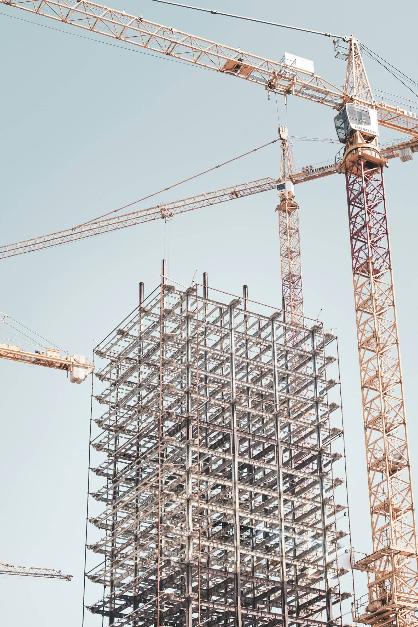A gray steel building frame near a tower crane during construction