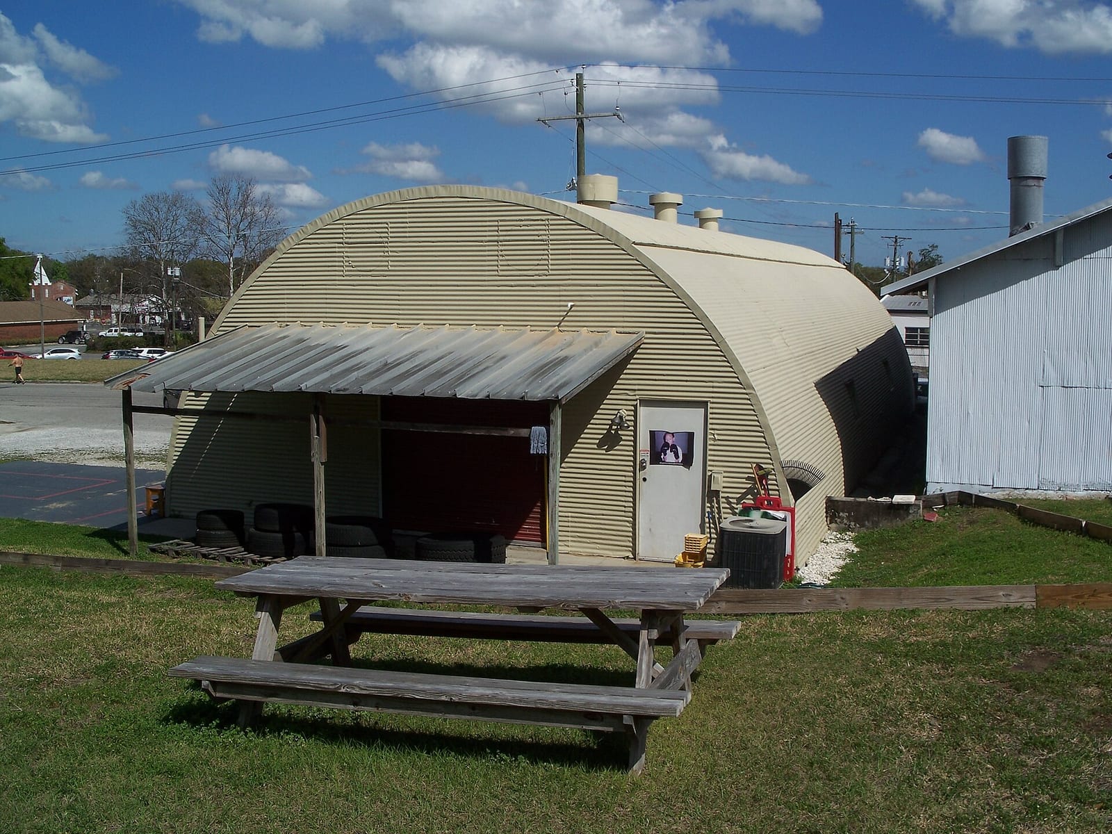 A quonset hut in civilian use with a picnic area outside