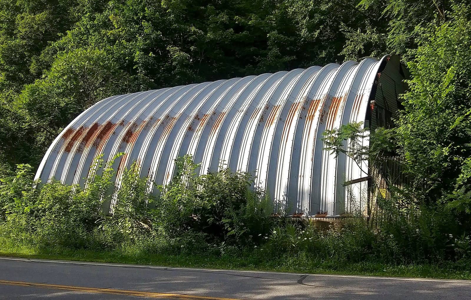 A quonset hut used as a garage along a rural road