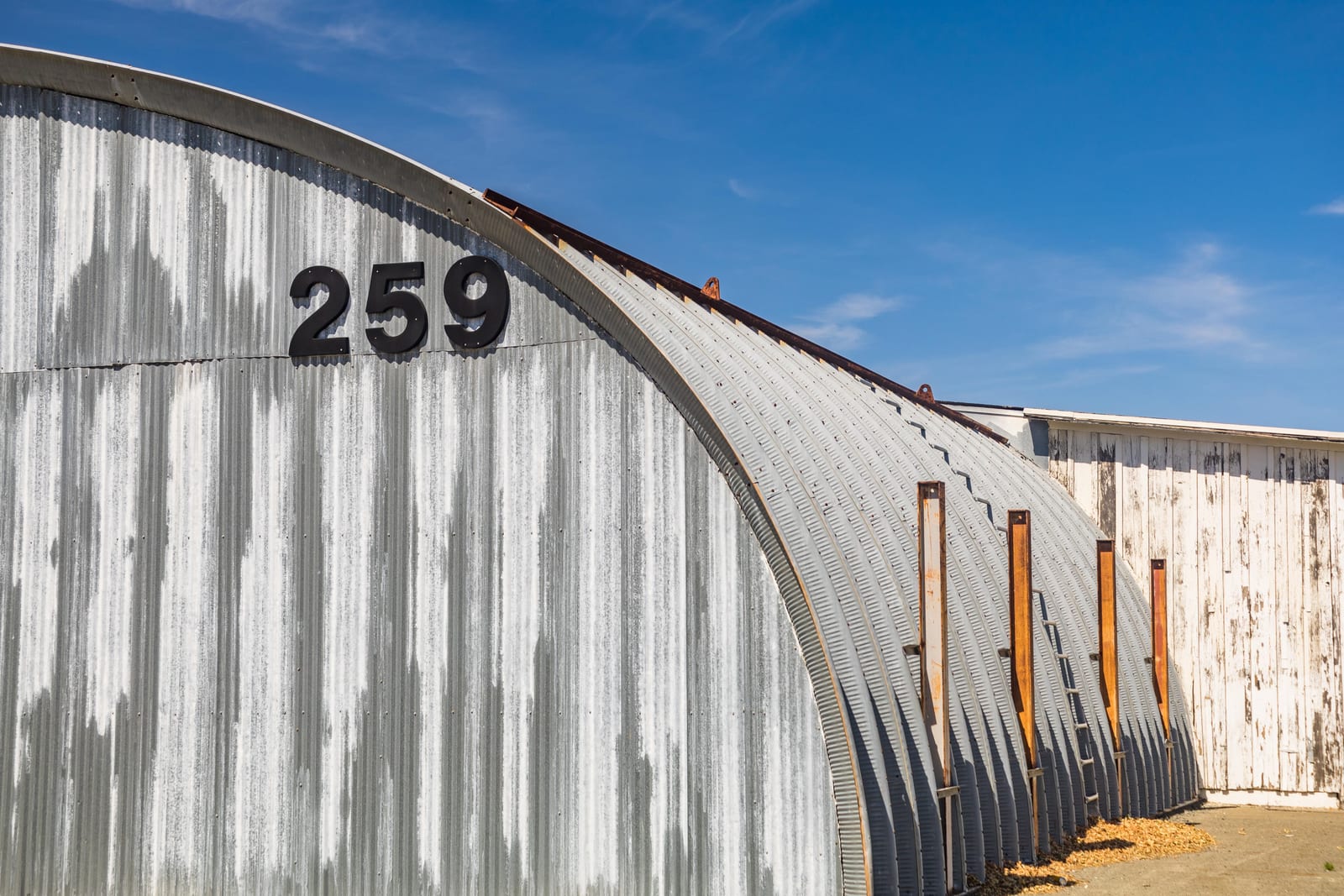 A gray corrugated metal warehouse building with a curved arch roofline