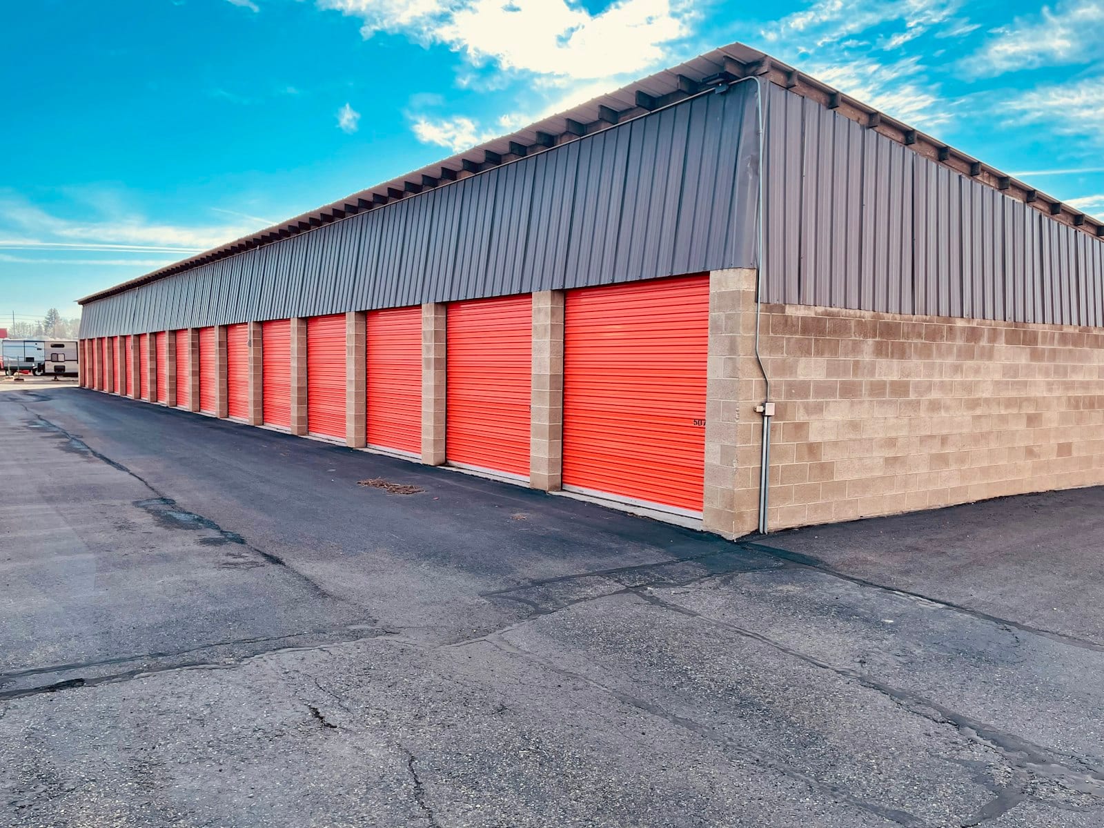 A self-storage facility exterior with a row of red roll-up unit doors