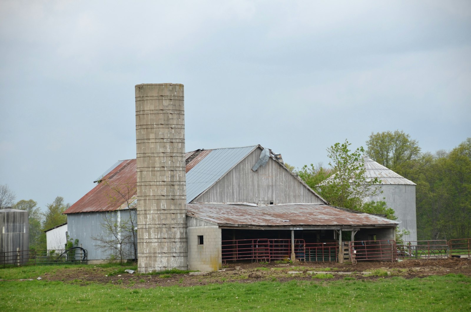 An old stock barn with a silo and grain storage bin on a farm